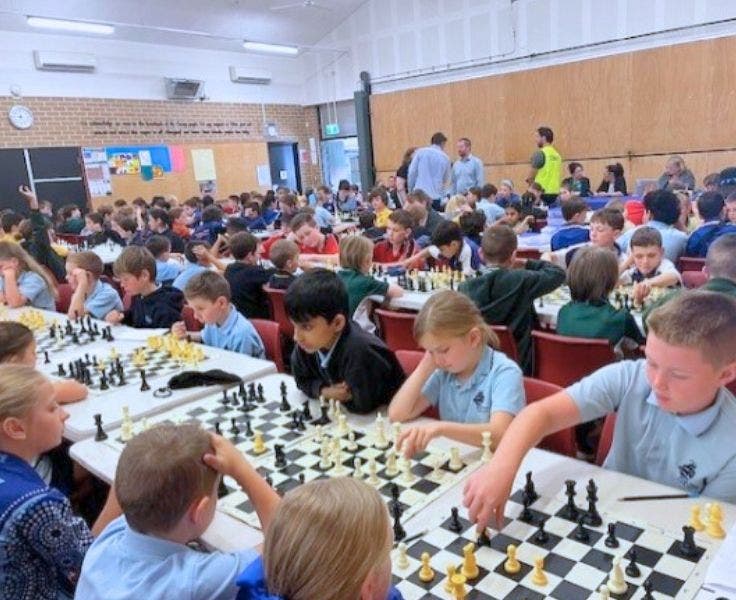 A school hall filled with students sitting at desks, playing chess