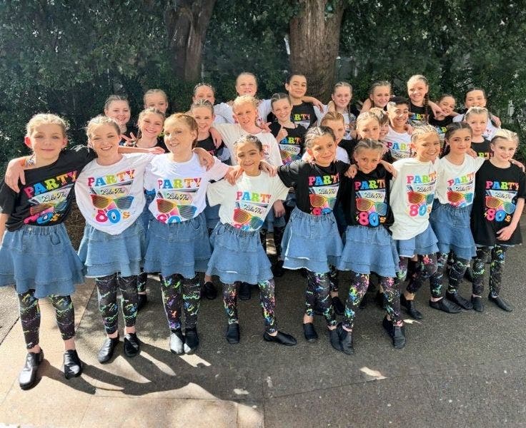 A photo of our dance group in denim skirts and white or black tops with colourful writing